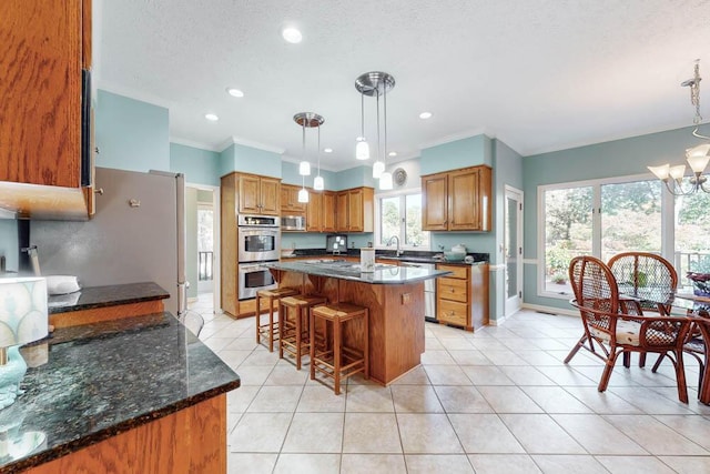 kitchen featuring an inviting chandelier, stainless steel appliances, hanging light fixtures, and a kitchen island