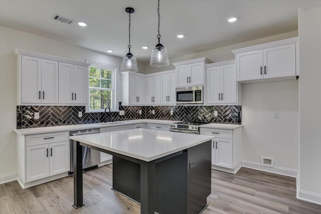 kitchen featuring white cabinetry, pendant lighting, stainless steel appliances, and a center island