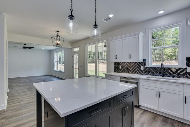 kitchen featuring sink, a center island, stainless steel dishwasher, pendant lighting, and white cabinets