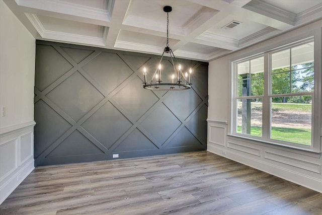 unfurnished dining area featuring coffered ceiling, an inviting chandelier, ornamental molding, beamed ceiling, and hardwood / wood-style floors