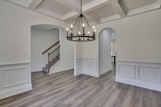 unfurnished dining area featuring beamed ceiling, ornamental molding, coffered ceiling, and light hardwood / wood-style flooring