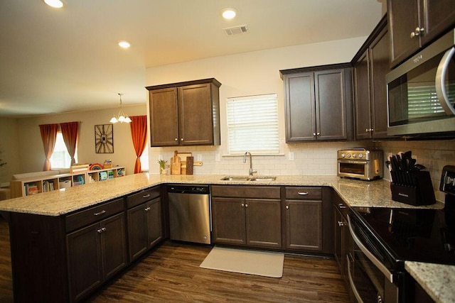 1144 George W Crawford Dr, Augusta, GA 30909 - kitchen with appliances with stainless steel finishes, a sink, a peninsula, tasteful backsplash, and dark brown cabinetry