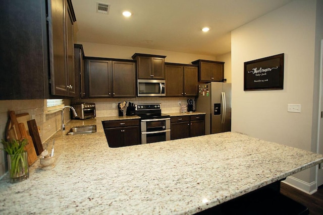 1144 George W Crawford Dr, Augusta, GA 30909 - kitchen featuring appliances with stainless steel finishes, a sink, dark brown cabinetry, backsplash, and recessed lighting