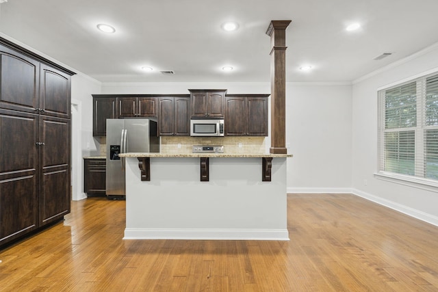4752 Storey Mill Rd, Hephzibah, GA 30815 - kitchen featuring appliances with stainless steel finishes, a kitchen bar, crown molding, decorative backsplash, and dark brown cabinetry