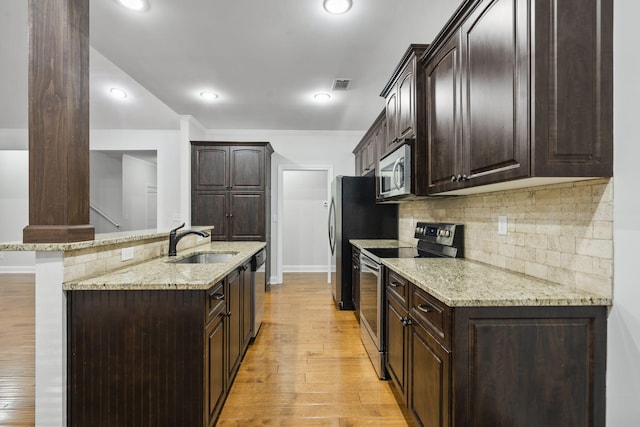 4752 Storey Mill Rd, Hephzibah, GA 30815 - kitchen with stainless steel appliances, dark brown cabinetry, light wood finished floors, tasteful backsplash, and a center island with sink