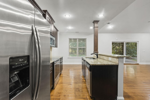 4752 Storey Mill Rd, Hephzibah, GA 30815 - kitchen featuring stainless steel appliances, light stone counters, light wood finished floors, dark brown cabinets, and recessed lighting