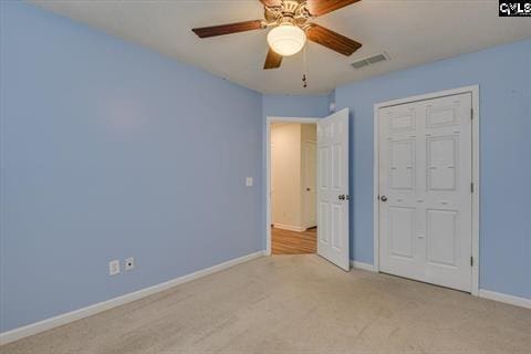 unfurnished bedroom featuring ceiling fan, a closet, and light carpet