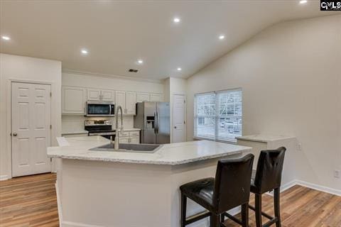 kitchen with white cabinets, a breakfast bar area, a large island, light hardwood / wood-style floors, and stainless steel appliances