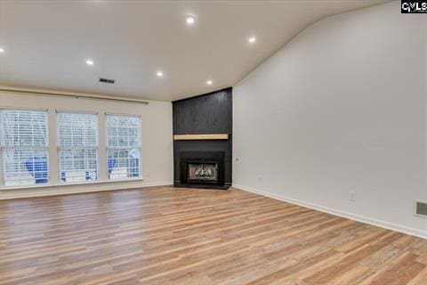 unfurnished living room with a large fireplace, lofted ceiling, and light hardwood / wood-style flooring