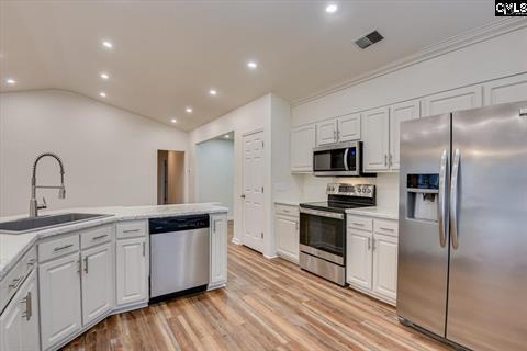 kitchen featuring appliances with stainless steel finishes, tasteful backsplash, vaulted ceiling, sink, and white cabinets