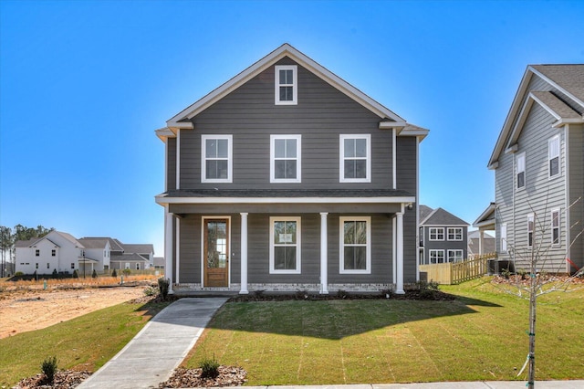 view of front of house featuring covered porch, a front lawn, and fence