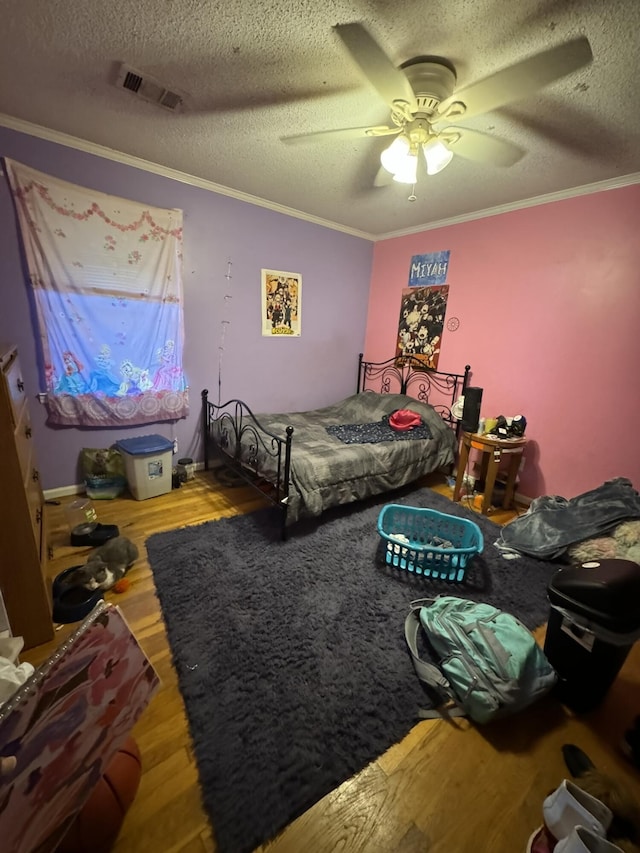 bedroom with ceiling fan, wood-type flooring, a textured ceiling, and ornamental molding