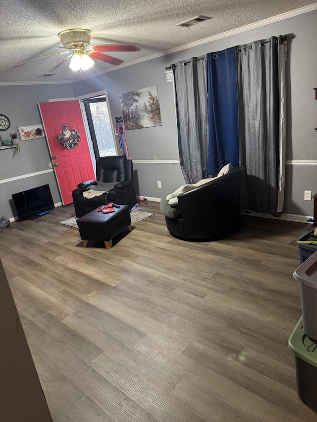 living area with hardwood / wood-style flooring, ceiling fan, crown molding, and a textured ceiling