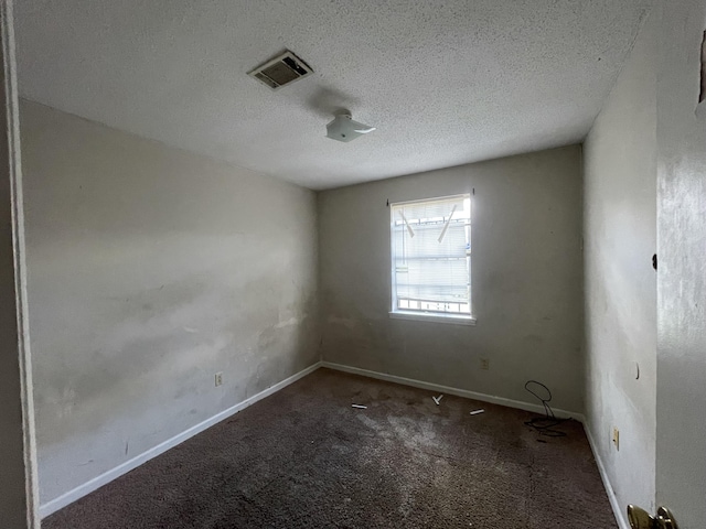 carpeted spare room with a textured ceiling, visible vents, and baseboards