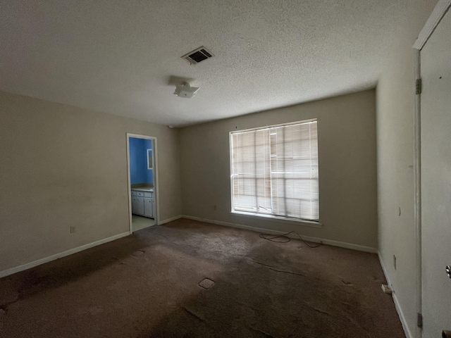 carpeted spare room with a textured ceiling, visible vents, and baseboards