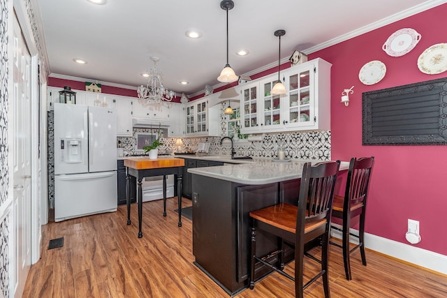 1300 Concord Ave, North Augusta, SC 29841 - kitchen with white fridge with ice dispenser, a peninsula, decorative backsplash, light wood finished floors, and ornamental molding