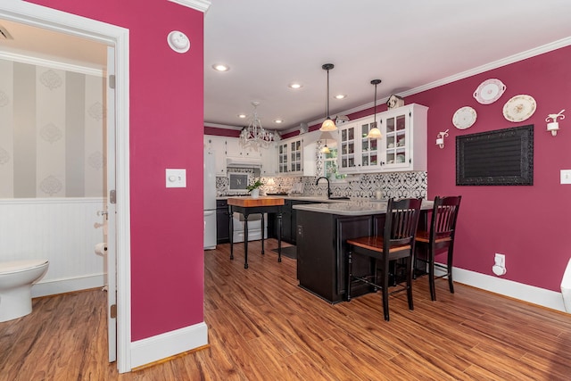 1300 Concord Ave, North Augusta, SC 29841 - kitchen with a peninsula, a kitchen bar, crown molding, wood finished floors, and white cabinets