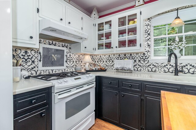 1300 Concord Ave, North Augusta, SC 29841 - kitchen with white gas stove, under cabinet range hood, dark cabinetry, and white cabinets