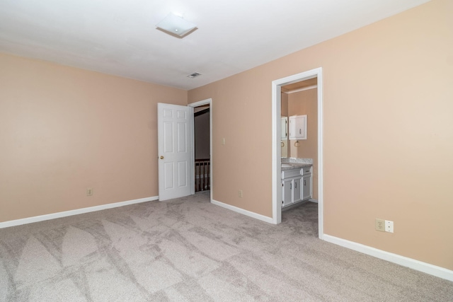 unfurnished bedroom with light colored carpet and ensuite bath