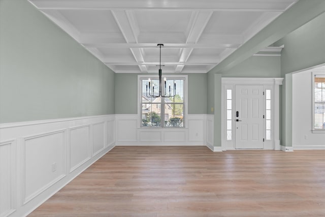 entrance foyer featuring beamed ceiling, coffered ceiling, a chandelier, and light hardwood / wood-style flooring