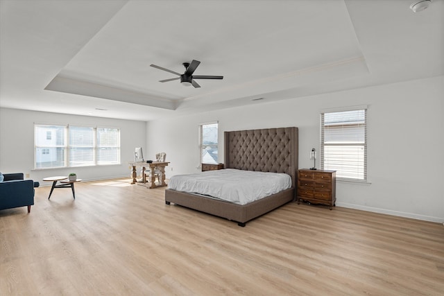 bedroom featuring a raised ceiling, ceiling fan, and light wood-type flooring