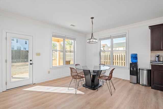 dining room with ornamental molding, light hardwood / wood-style floors, and a healthy amount of sunlight