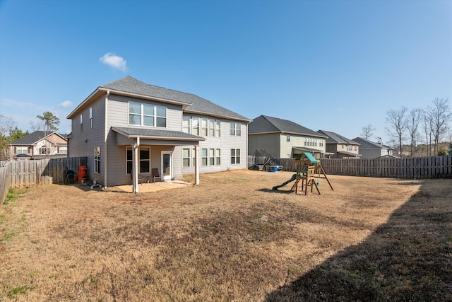 back of property featuring a yard, a patio, and a playground