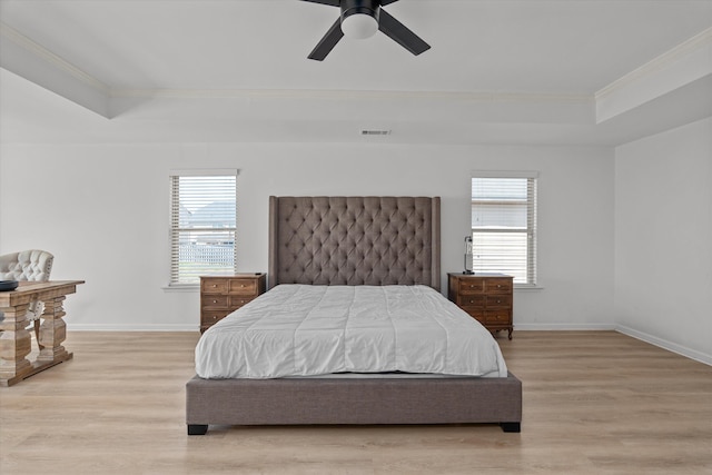 bedroom with crown molding, ceiling fan, a tray ceiling, and light hardwood / wood-style floors