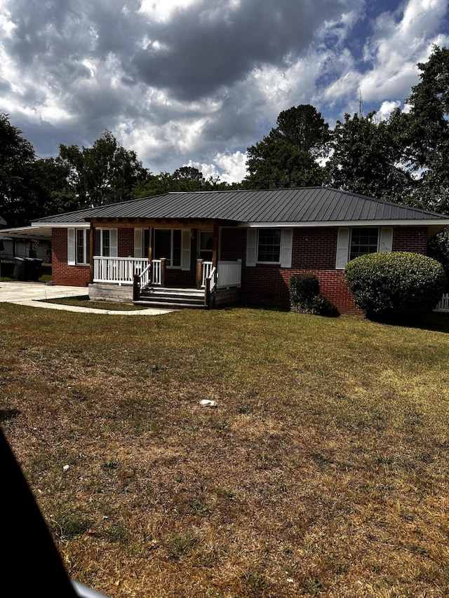 ranch-style house featuring brick siding, a porch, a front yard, a carport, and metal roof
