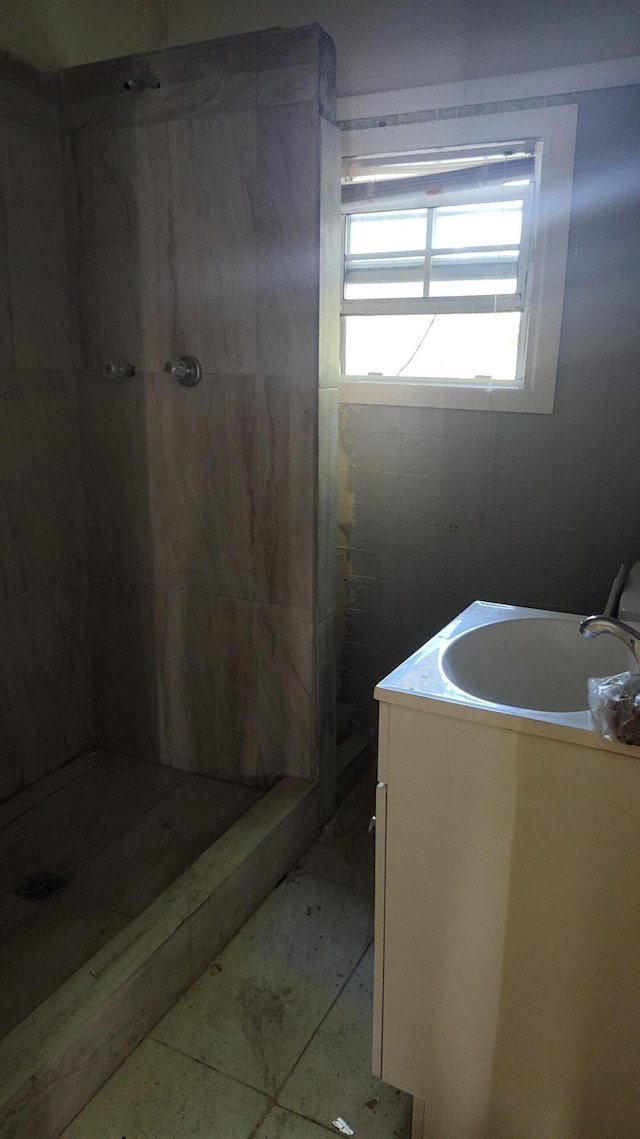 bathroom featuring tile patterned flooring, vanity, and tiled shower