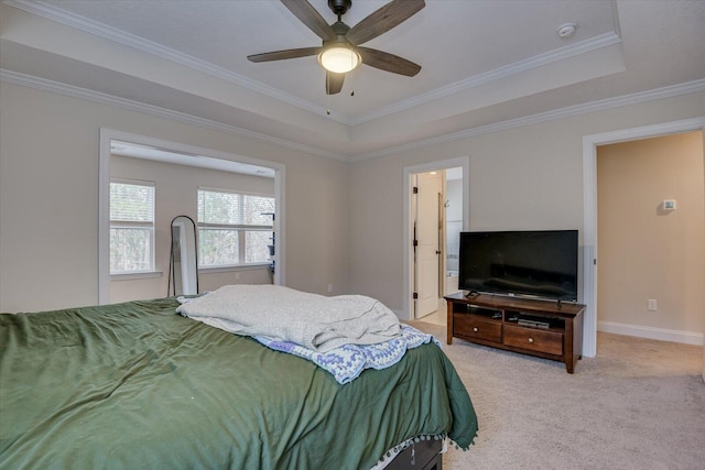 bedroom featuring ensuite bathroom, a tray ceiling, crown molding, ceiling fan, and light carpet