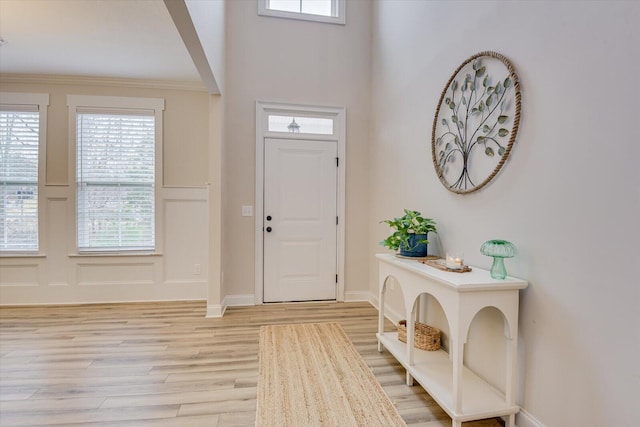 entryway with crown molding and light hardwood / wood-style flooring