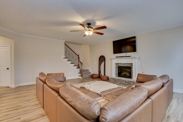 living room with a fireplace, ceiling fan, crown molding, and light hardwood / wood-style flooring