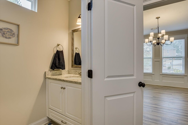 bathroom with vanity, an inviting chandelier, a healthy amount of sunlight, and hardwood / wood-style flooring