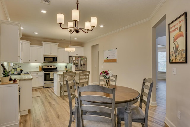 dining room featuring an inviting chandelier, light hardwood / wood-style floors, and crown molding