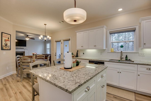 kitchen featuring a center island, white cabinetry, hanging light fixtures, and sink