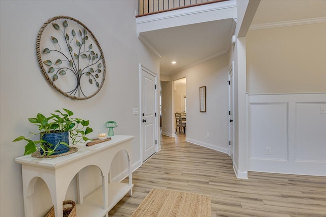 hallway with crown molding and light hardwood / wood-style flooring