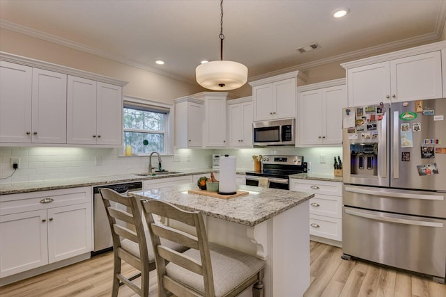 kitchen with sink, stainless steel appliances, decorative light fixtures, and white cabinets