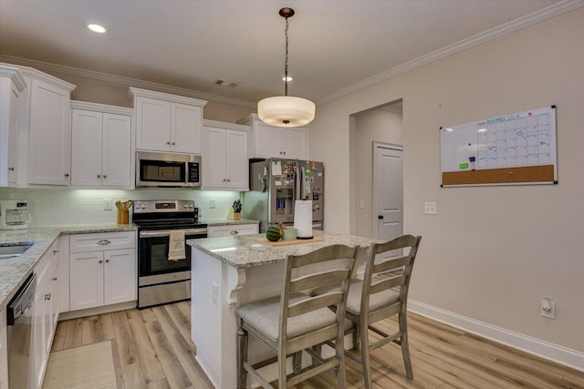 kitchen with light hardwood / wood-style flooring, decorative light fixtures, stainless steel appliances, decorative backsplash, and white cabinetry