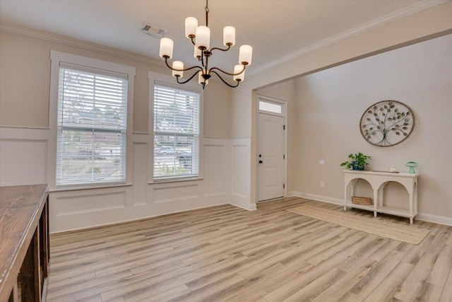 unfurnished dining area with ornamental molding, light hardwood / wood-style floors, and a notable chandelier