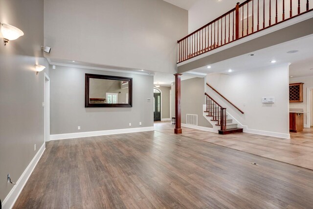 2288 William Few Pkwy, Evans, GA 30809 - unfurnished living room with a towering ceiling, stairs, wood finished floors, baseboards, and recessed lighting