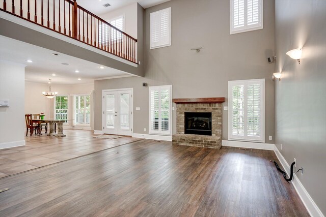 2288 William Few Pkwy, Evans, GA 30809 - unfurnished living room with a towering ceiling, baseboards, wood finished floors, a chandelier, and a brick fireplace