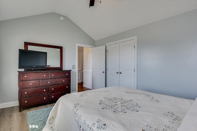 bedroom with ceiling fan, a closet, vaulted ceiling, and hardwood / wood-style flooring