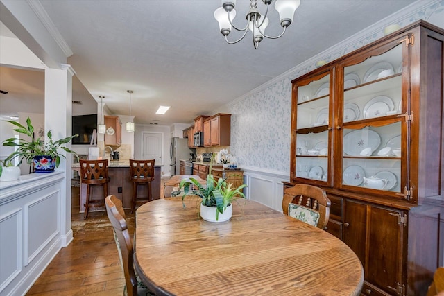 dining area featuring dark hardwood / wood-style flooring, ornamental molding, and a notable chandelier