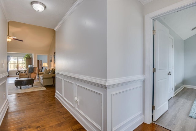 corridor with lofted ceiling, dark wood-type flooring, and crown molding