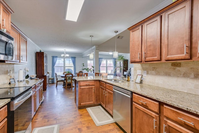 kitchen with decorative light fixtures, light stone countertops, appliances with stainless steel finishes, and sink