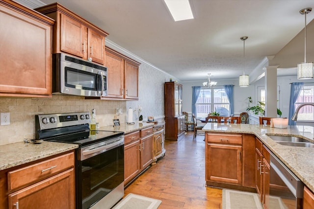 kitchen with stainless steel appliances, sink, hanging light fixtures, ornamental molding, and a chandelier