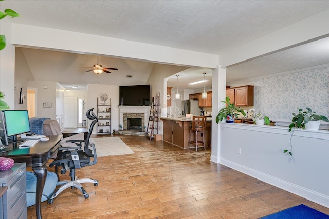 office space with ceiling fan, a fireplace, wood-type flooring, sink, and a textured ceiling