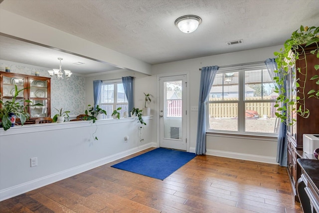 entryway featuring hardwood / wood-style flooring, plenty of natural light, a textured ceiling, and a notable chandelier