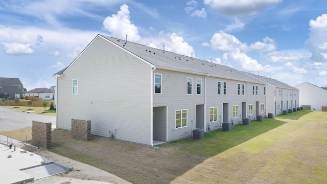 back of property featuring cooling unit and a lawn